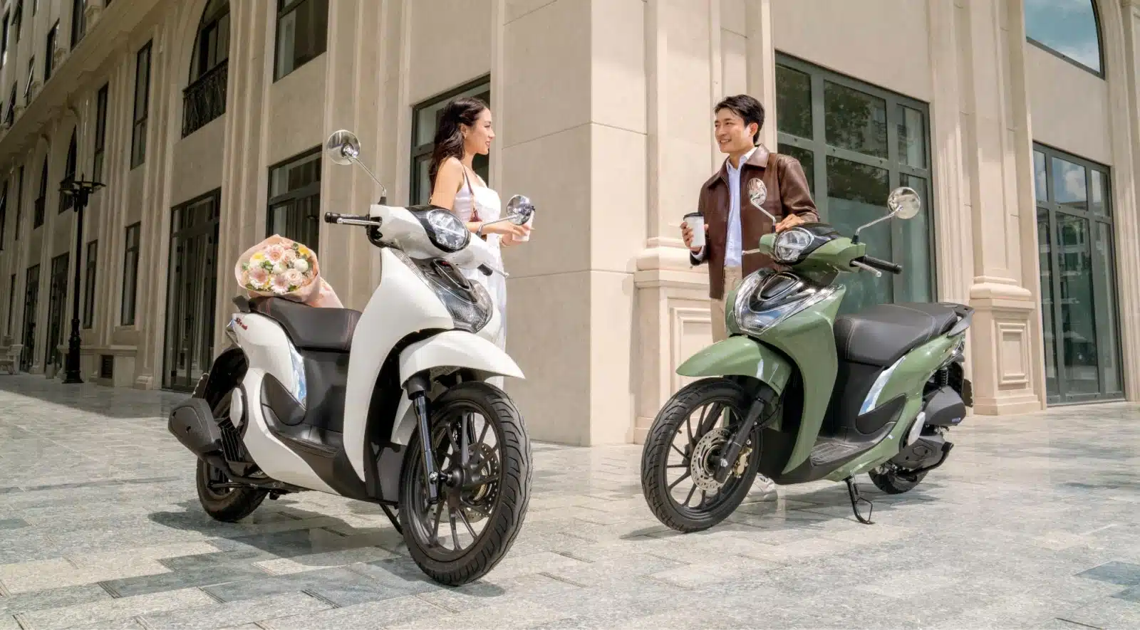 Hai xe SH Mode 2027 màu trắng và màu xanh đậu bên đường phố, đôi bạn trẻ đứng cạnh